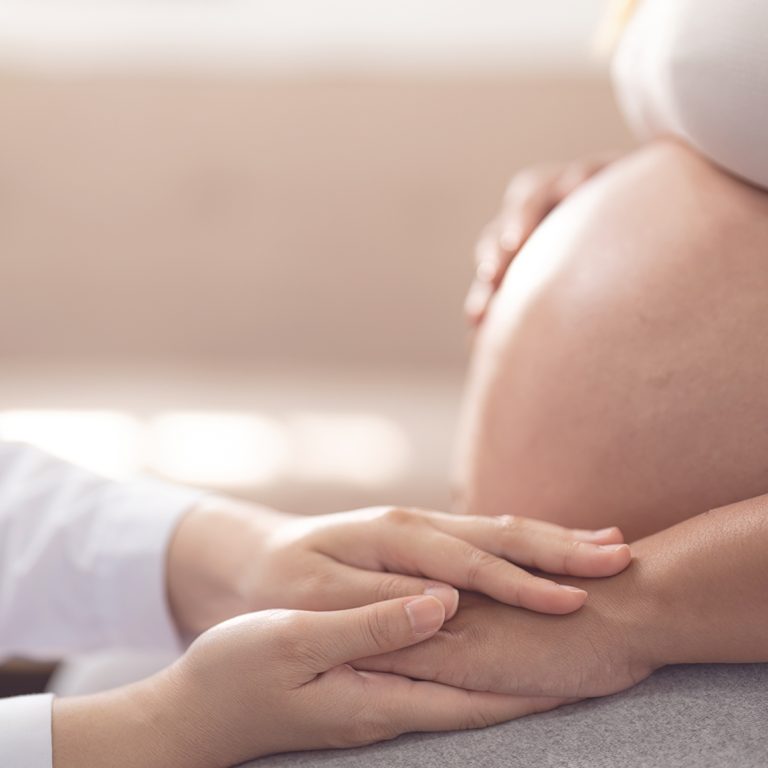 Healthcare, pregnancy and hands of doctor with pregnant woman for support, comfort and compassion. Medical care, family home and top view of health worker holding hands with maternal patient.